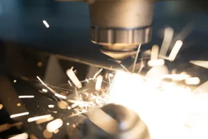 Close-up of industrial laser cutting metal, shooting sparks while producing clean, precise edges — Dallas Precision Machining CNC machine shop.