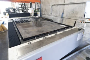 Large sheet of metal on a CNC cutting table in a fabrication shop, staged for laser/waterjet cutting and downstream forming — Dallas Precision Machining CNC machine shop.