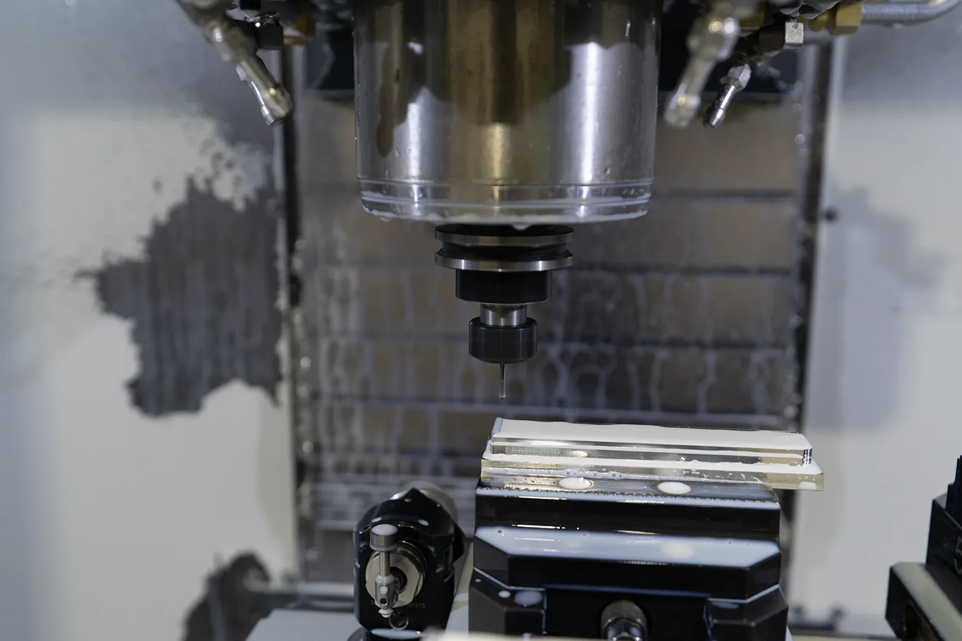 CNC spindle positioned over a vise and workpiece inside a vertical machining center during setup at Dallas Precision Machining.